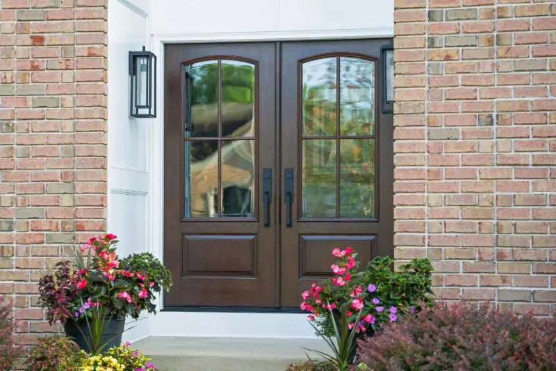 ProVia double entry doors with a dark wood-look finish and decorative glass on a brick home.