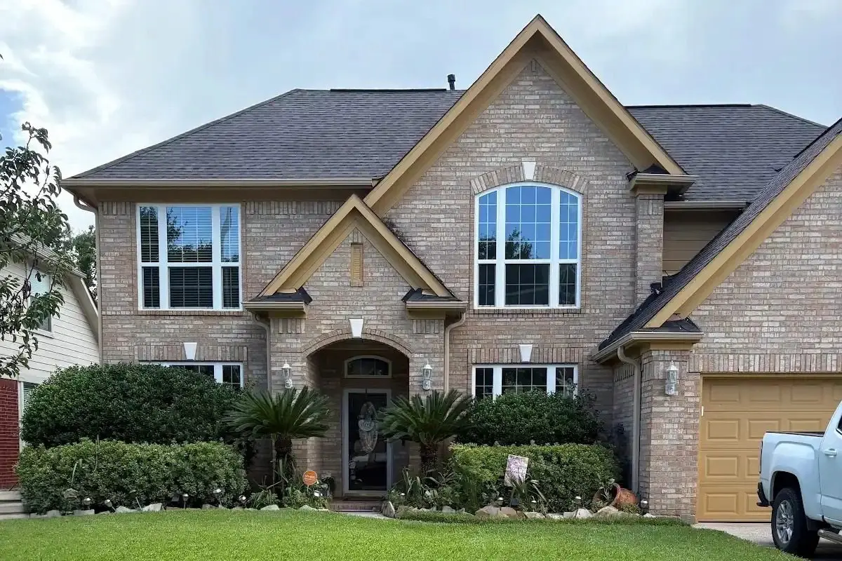 Two-story Houston home with white replacement windows, tan siding, and brick exterior