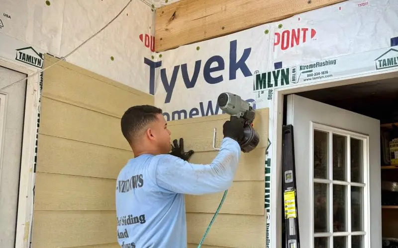 Allied Exteriors installer with a nail gun applying siding.