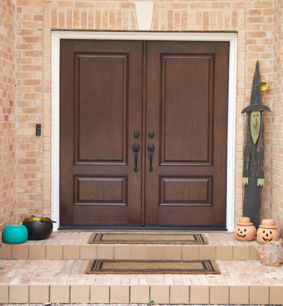 Dark wood-look fiberglass double entry doors on a brick home.