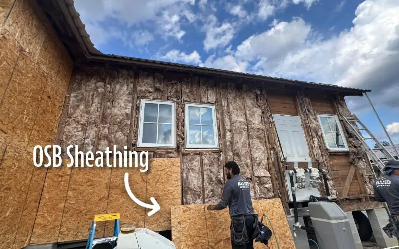 Los instaladores de Allied Exteriors colocan un revestimiento de OSB en una pared exterior expuesta durante un proyecto de reemplazo de revestimiento.