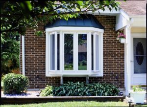 White bay window on a brick home with black roof