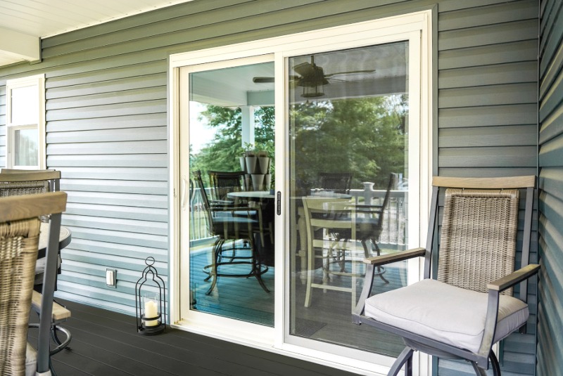 White ProVia sliding glass patio door installed on a covered porch with gray siding.