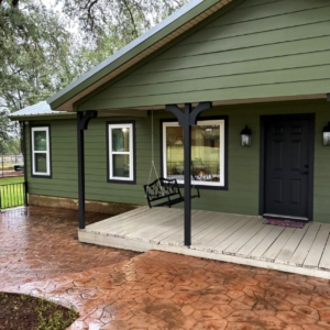 White double-hung replacement windows installed by Allied Exteriors on a green-sided home in Bertram, Texas.