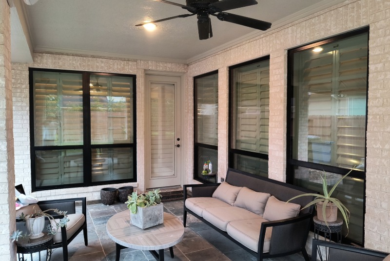 Back patio of a home with white washed brick and black windows that compliment the contrast of the home.