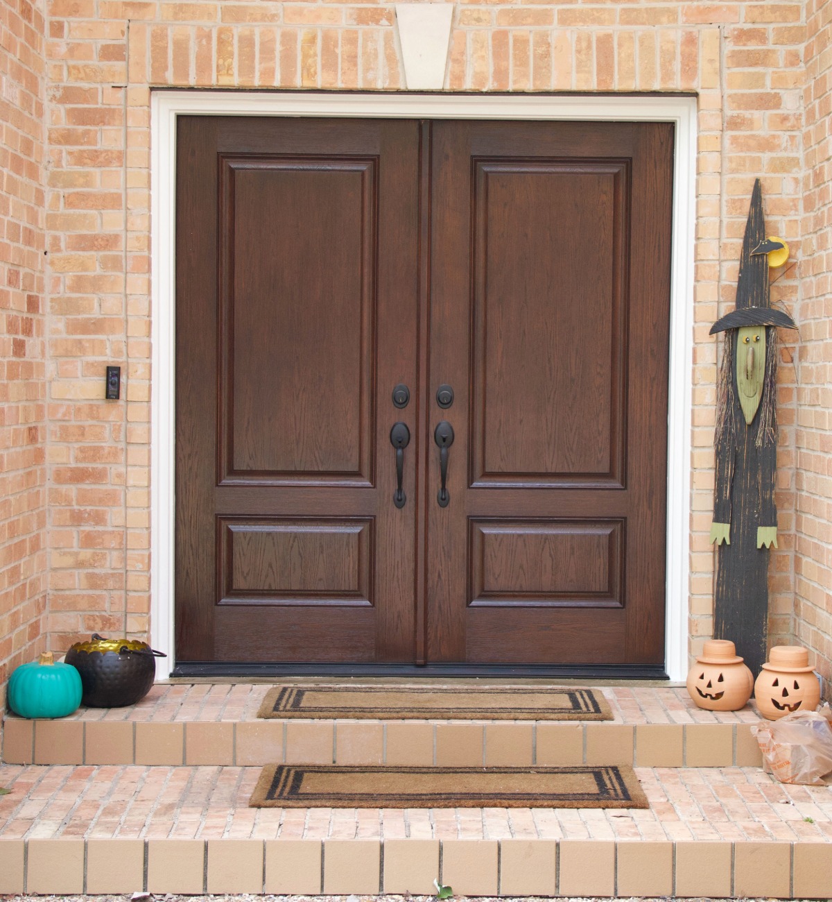 Fiberglass dark wood look door on a brick home with fall decor