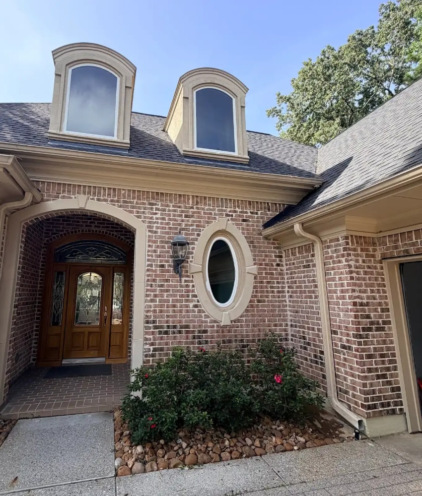 Brick home with tan gutters and downspouts