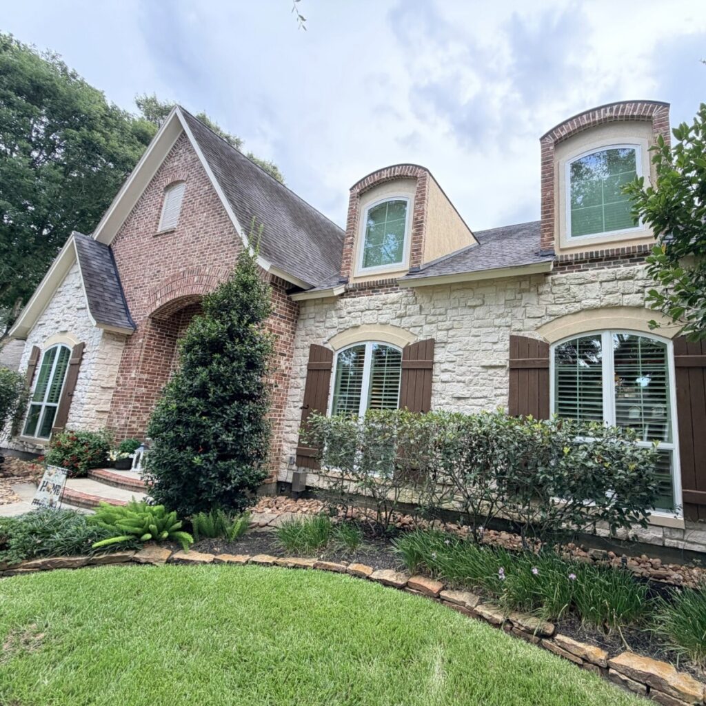 White replacement windows with arched specialty windows installed by Allied Exteriors on a brick home in Tomball, Texas.
