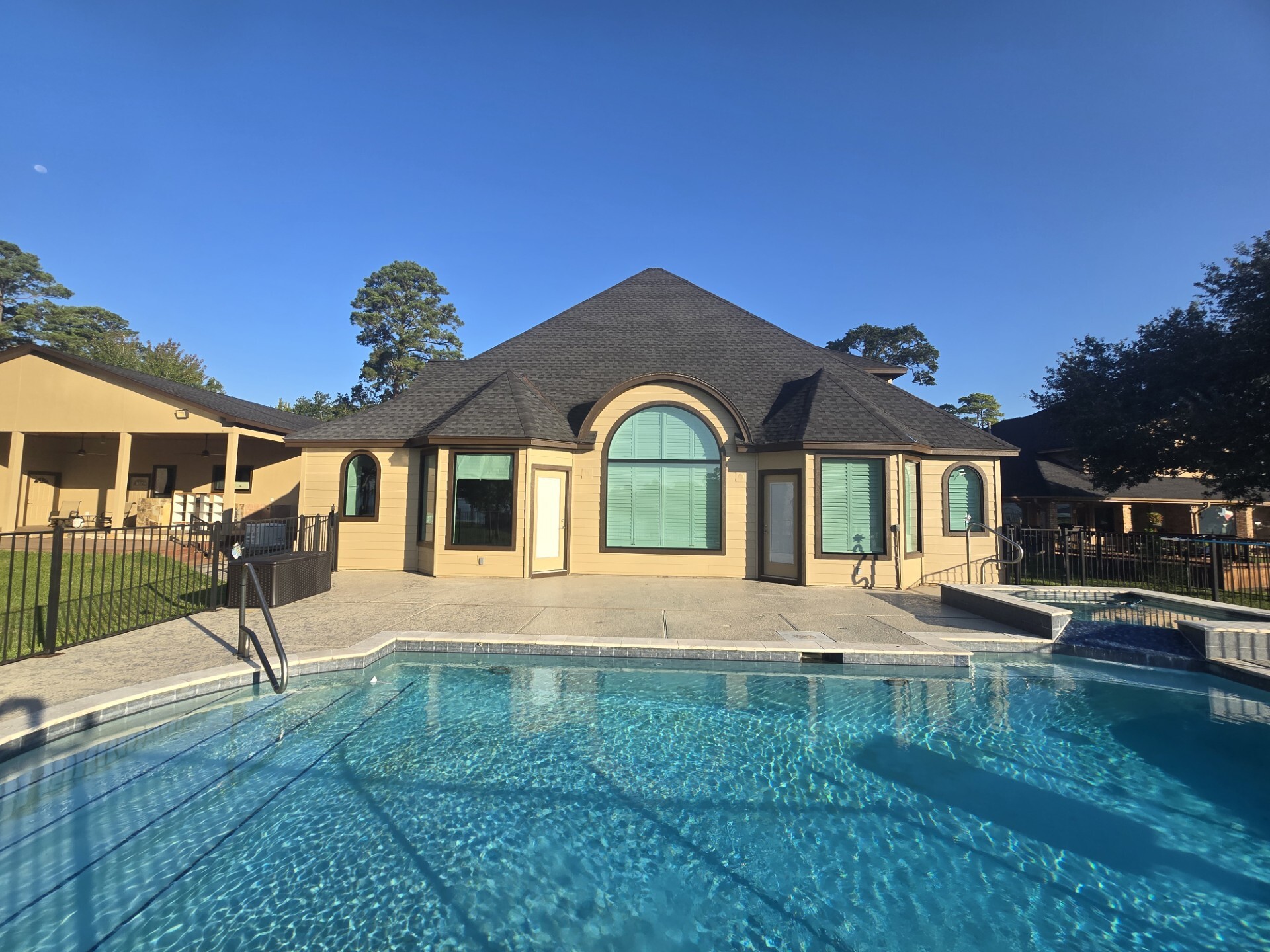 Back of home with arch bronze windows and pool