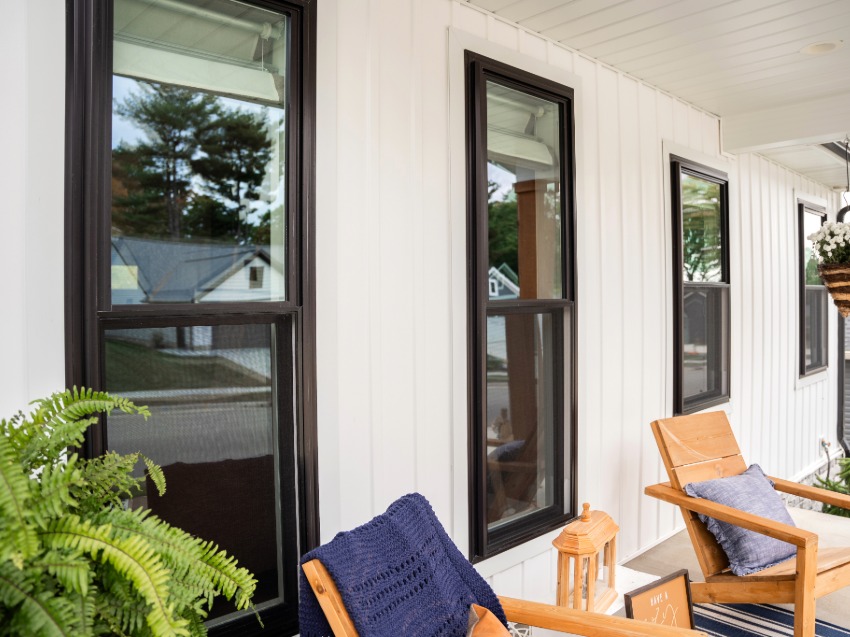 black window on white home with wooden rocking chair on porch