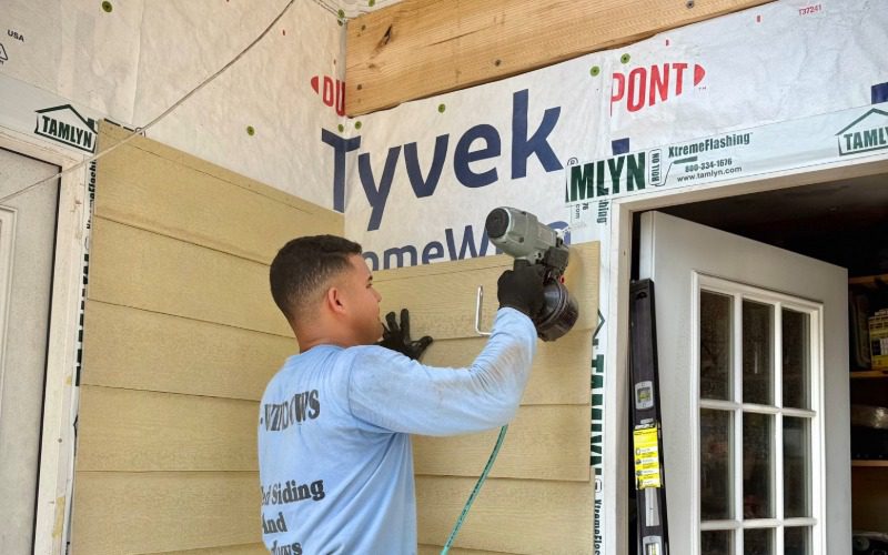 Allied Exteriors installer with a nail gun applying siding.